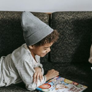 Side view of cheerful African American boy looking at illustration of book with fascinating fairytale