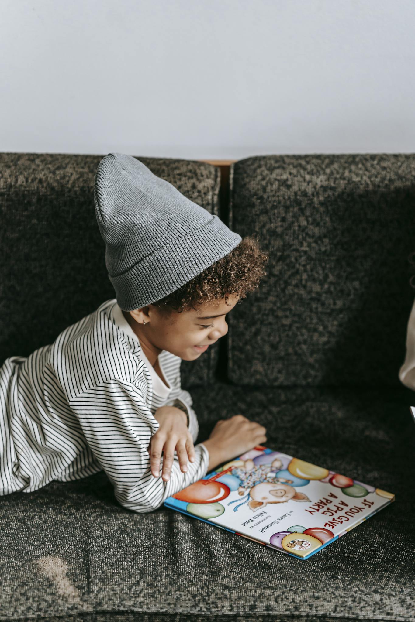 Side view of cheerful African American boy looking at illustration of book with fascinating fairytale