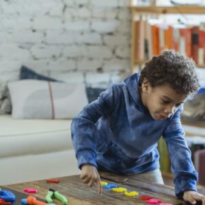 Young boy arranging colorful math shapes on a table, learning and playing.