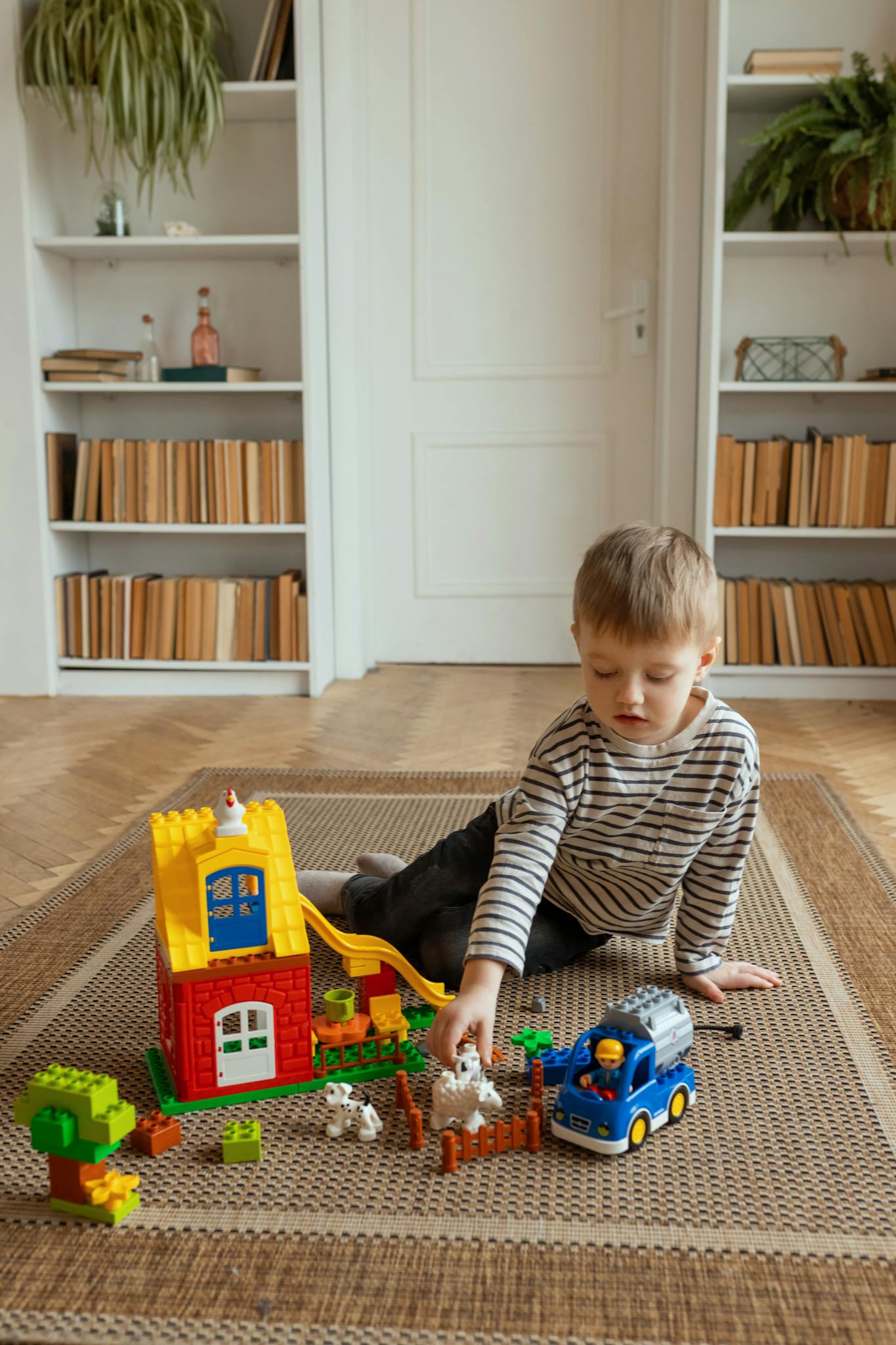 Young boy engaging with colorful blocks on rug indoors.
